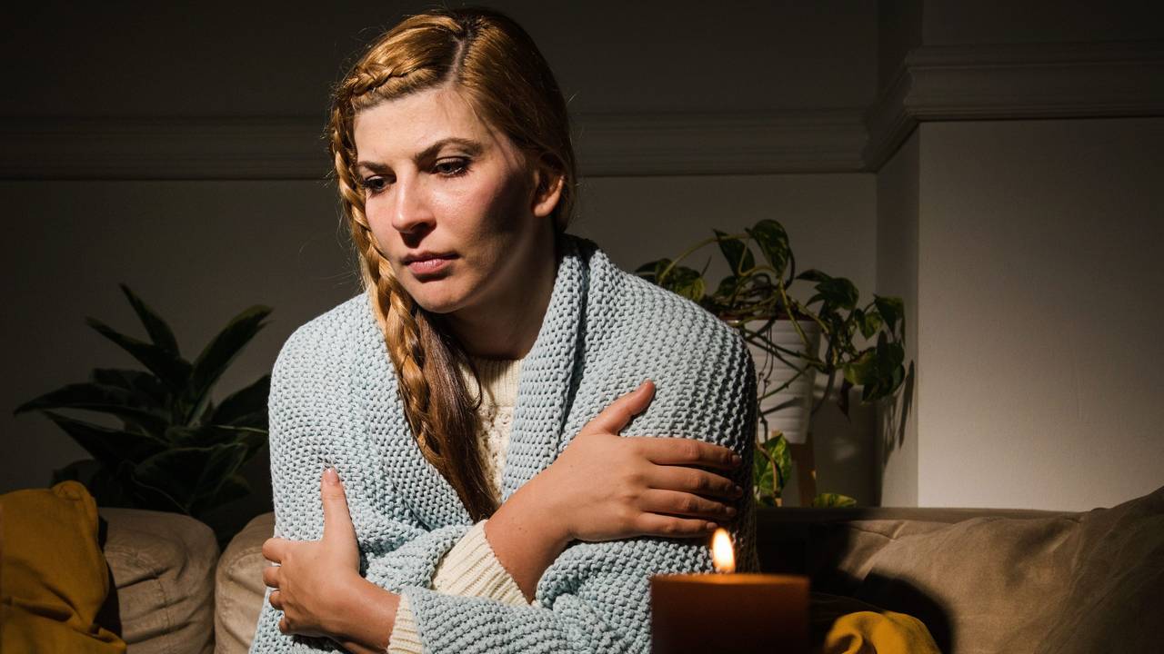 Eine Frau sitzt mit verschränkten Armen auf einer Couch.