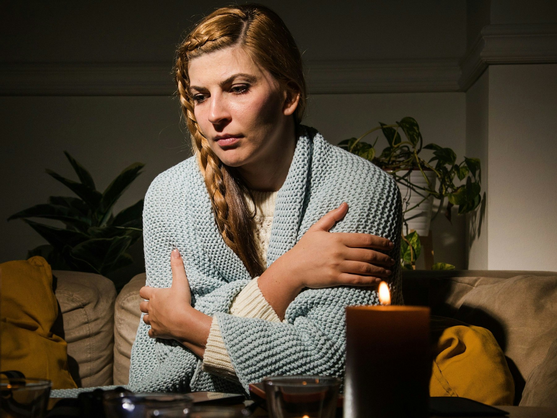 Eine Frau sitzt mit verschränkten Armen auf einer Couch.