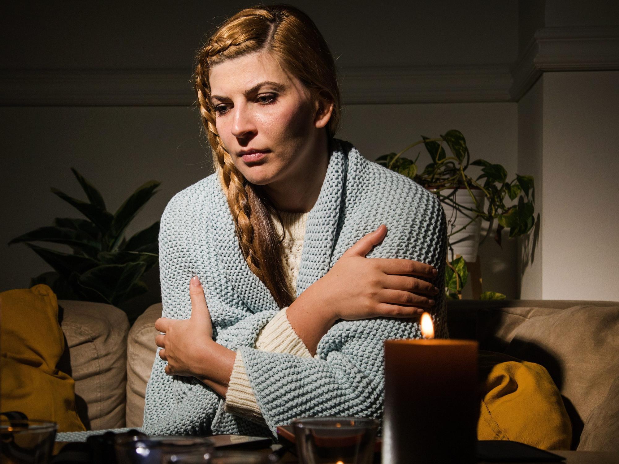 Eine Frau sitzt mit verschränkten Armen auf einer Couch.