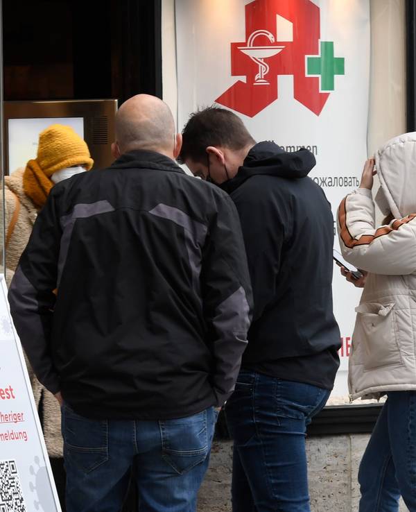 Menschen stehen vor einer Apotheke Schlange.