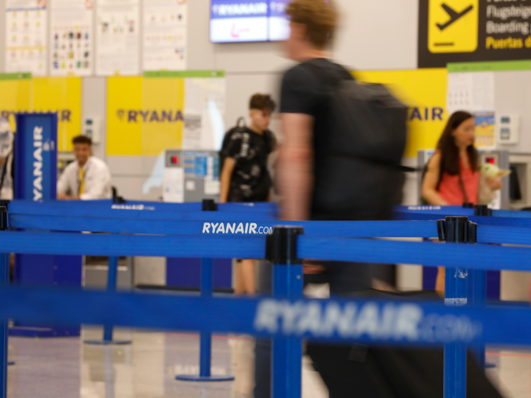 Menschen gehen zum Abfertigungsschalter von Ryanair am Flughafen von Palma de Mallorca.