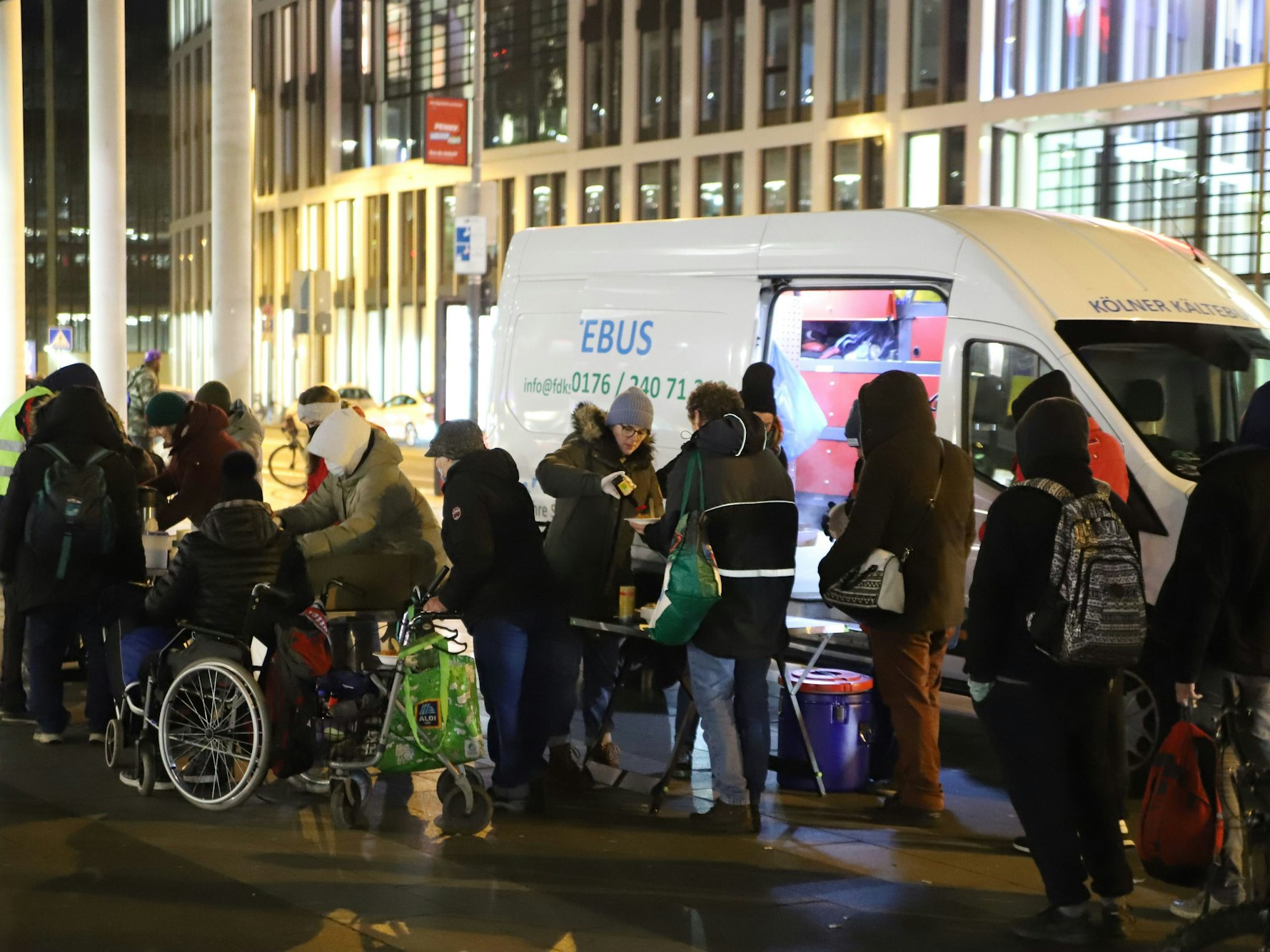 Menschen stehen in einer Warteschlange vor einem Bus.