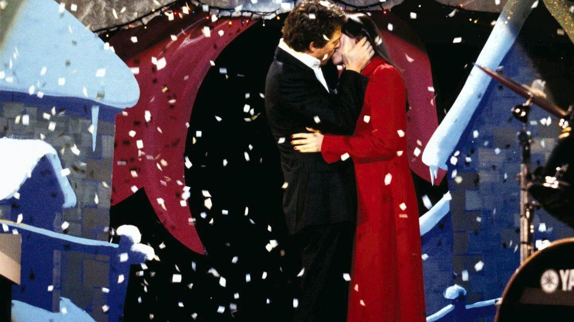 Der englische Premierminister (gespielt von Hugh Grant) küsst seine Angestellte Natalie (gespielt von Martine McCutcheon) auf einer Bühne. Von oben rieselt weißes Konfetti auf die beiden herab.