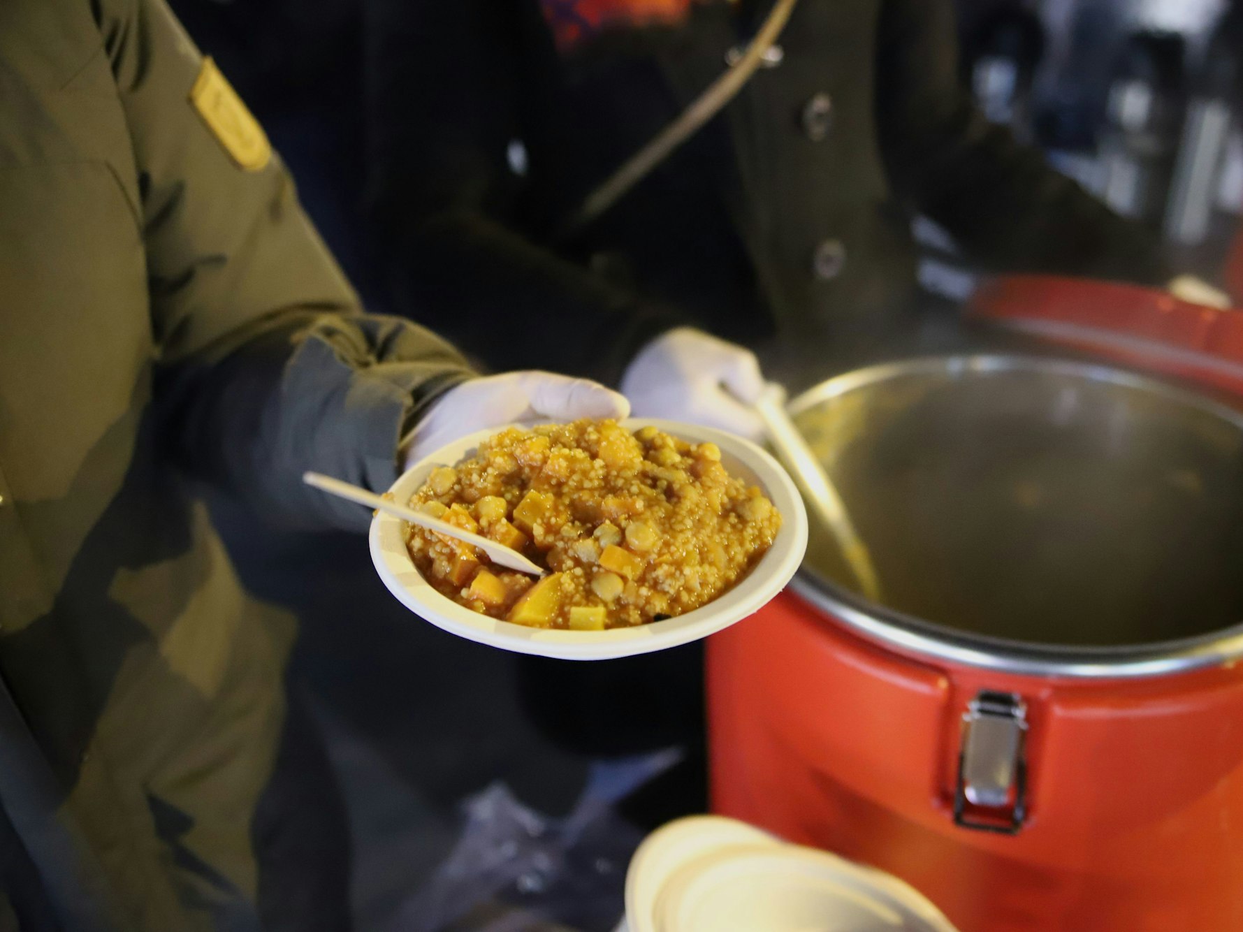 Eine Frau hält einen Teller mit Eintopf in der Hand.