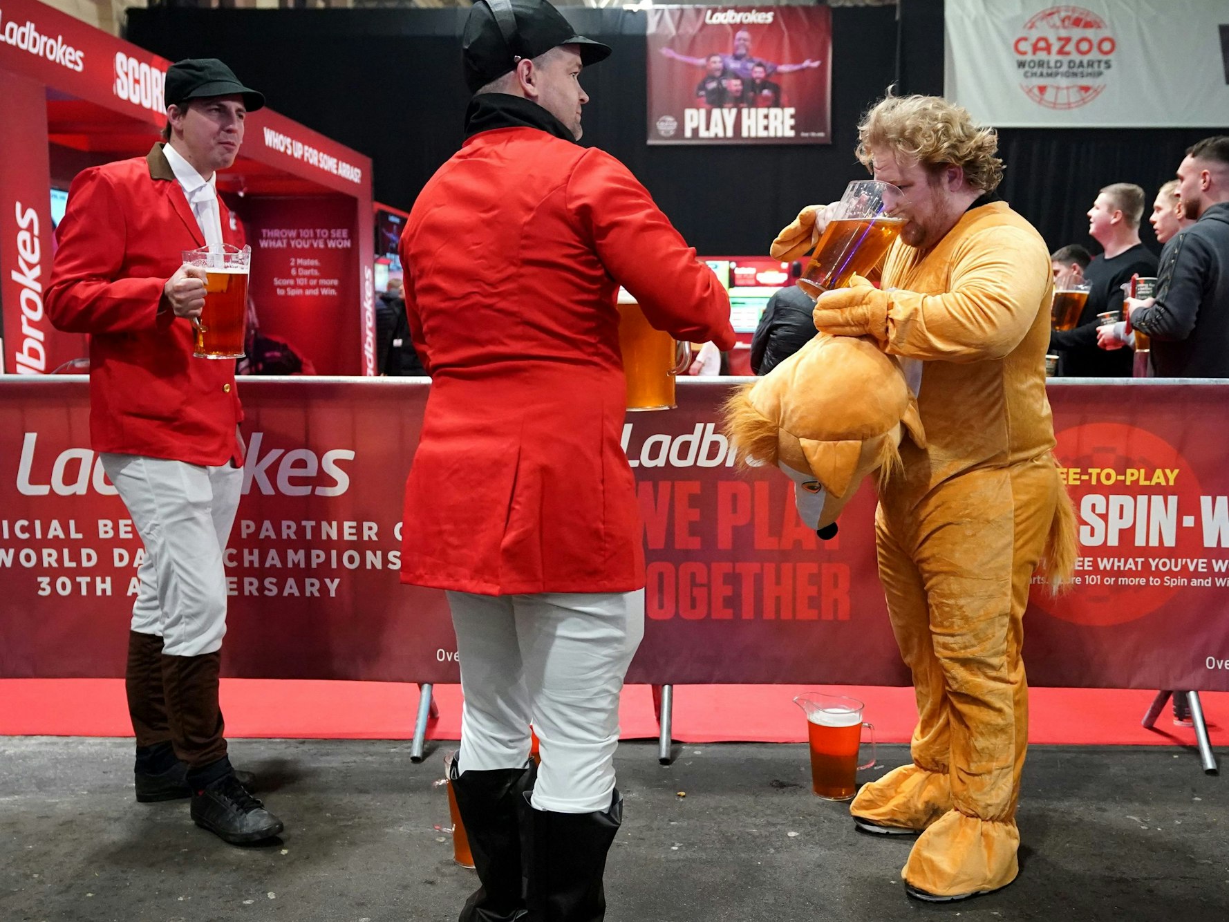 Darts-Fans in Kostümen trinken während des zweiten Tages der Cazoo World Darts Championship im Alexandra Palace Bier.