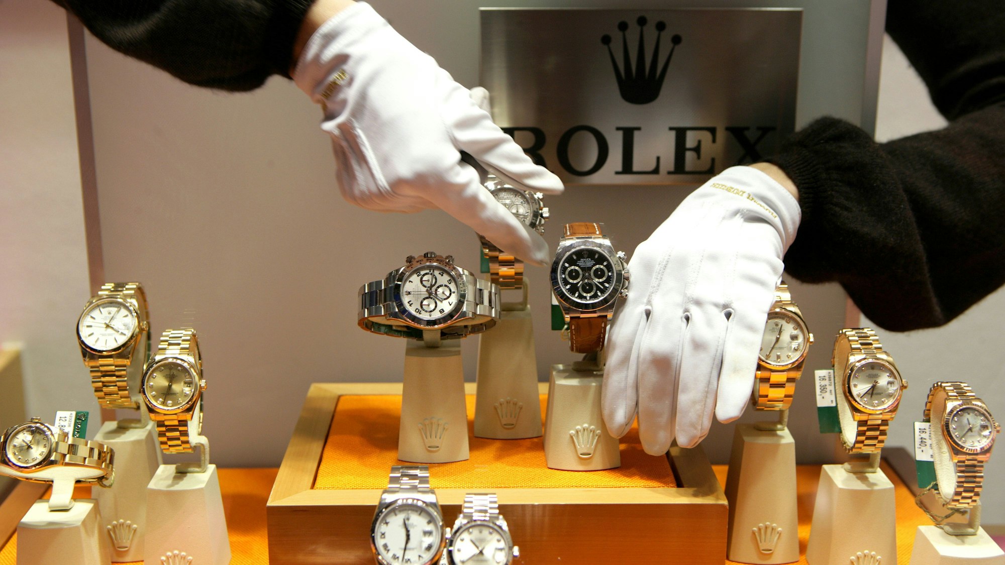 Mit weißen Handschuhen werden Luxusuhren der Schweizer Uhrenmanufaktur Rolex in einem Schaufenster plaziert.