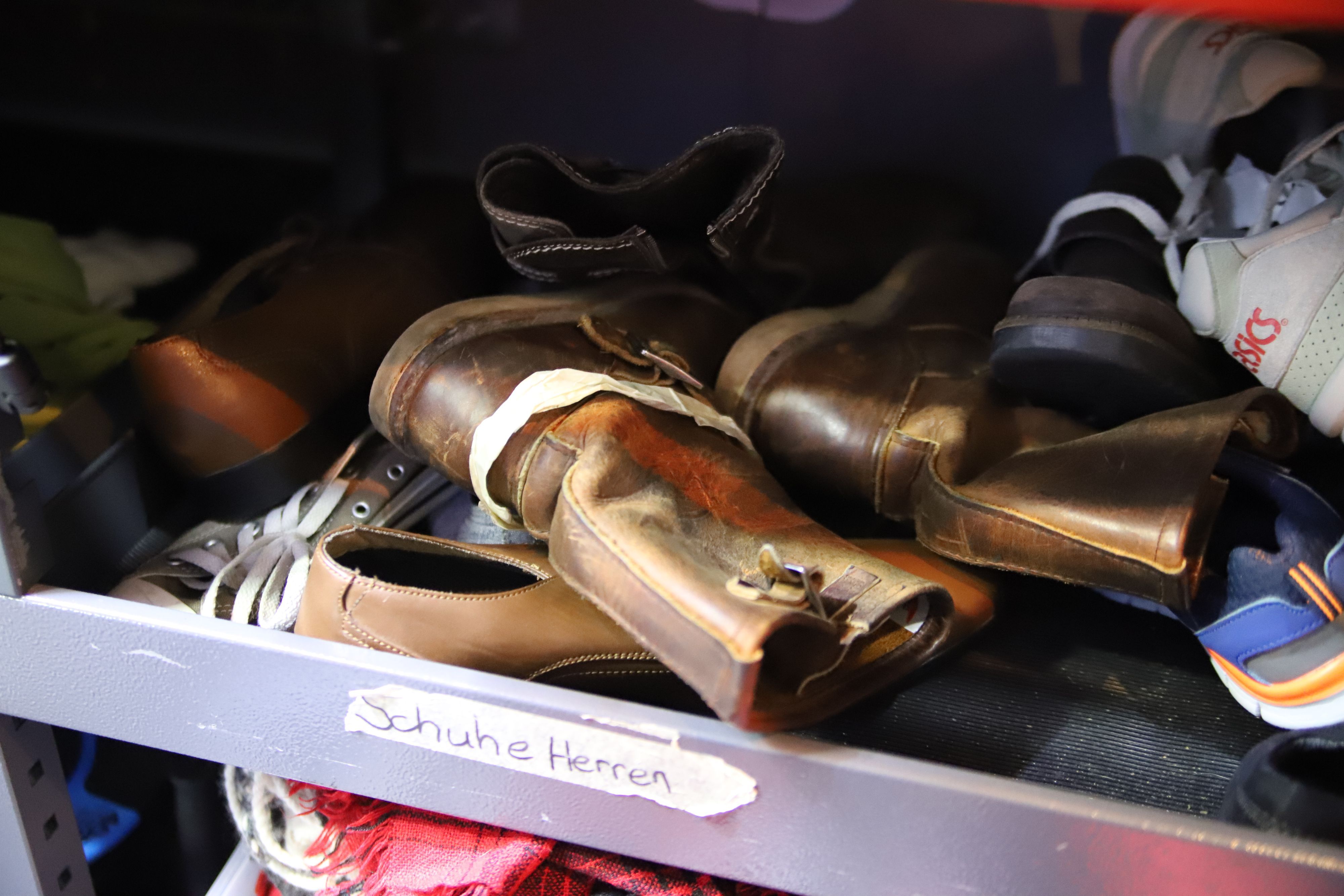 Ein Fach im Kältebus, in dem Herrenschuhe zur Verteilung liegen.