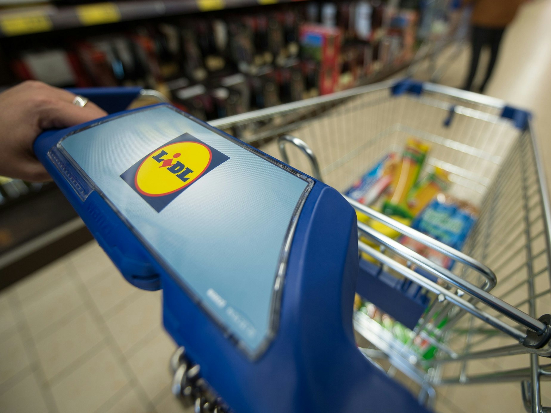 Ein Kunde schiebt in einer Filiale des Lebensmitteldiscounters Lidl einen Einkaufswagen durch die Regalreihen.
