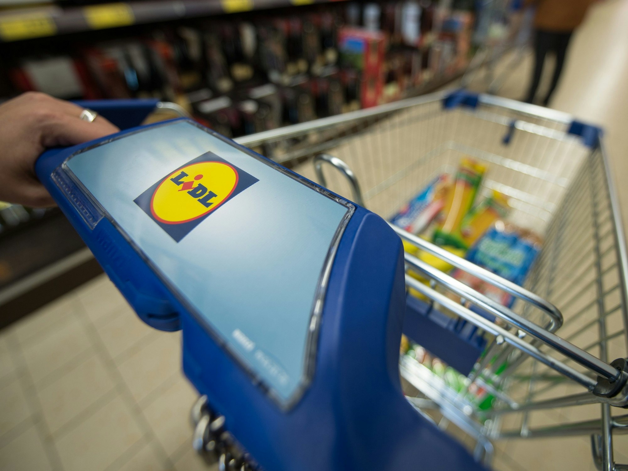 Ein Kunde schiebt in einer Filiale des Lebensmitteldiscounters Lidl einen Einkaufswagen durch die Regalreihen.