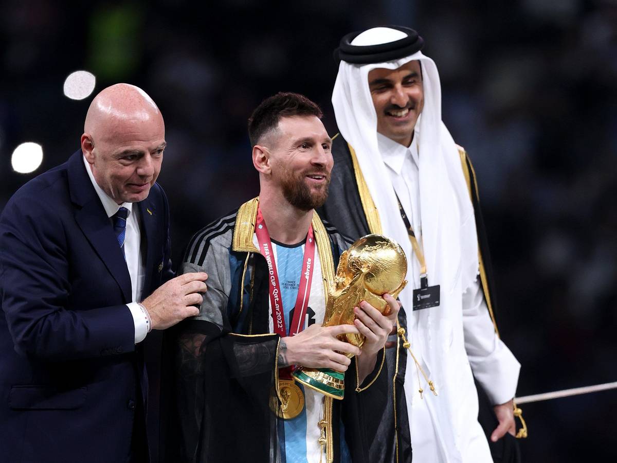 Lionel Messi steht bei der Siegerehrung mit dem WM-Pokal neben Fifa-Präsident Gianni Infantino und Katars Emir Tamim bin Hamad Al Thani.