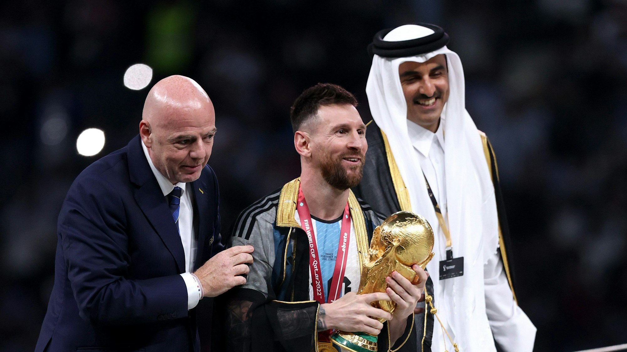 Lionel Messi steht bei der Siegerehrung mit dem WM-Pokal neben Fifa-Präsident Gianni Infantino und Katars Emir Tamim bin Hamad Al Thani.