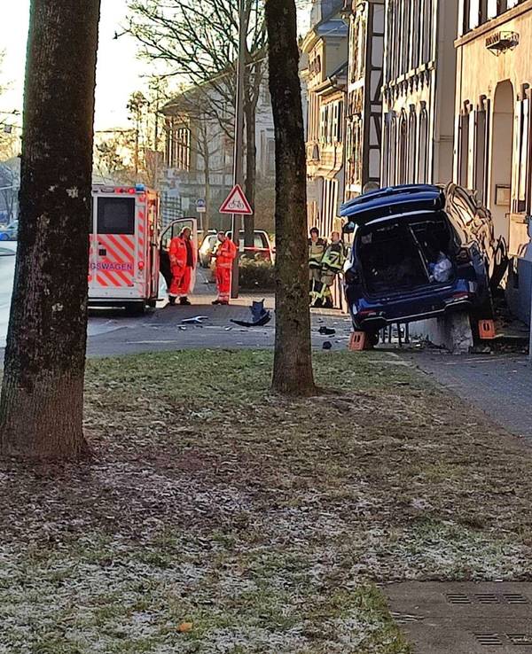 Nach einem Unfall hängt ein stark beschädigtes Auto auf der Treppe zu einem Haus fest.