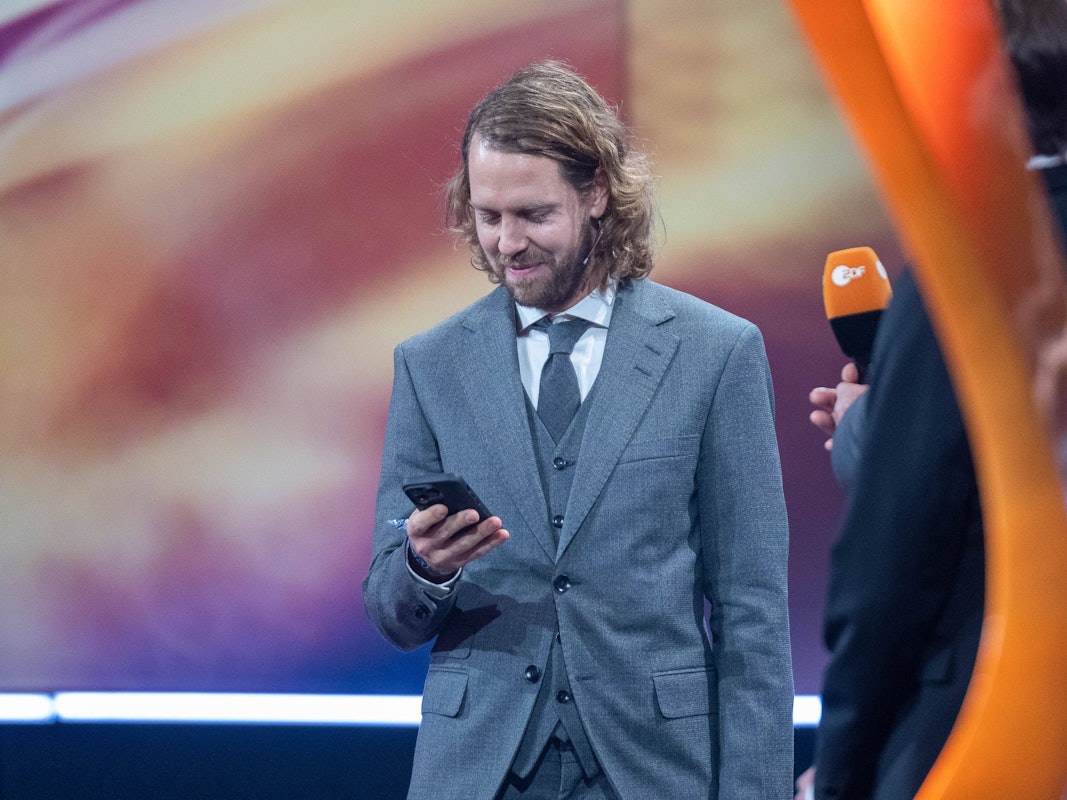 Sebastian Vettel schaut auf sein Handy.