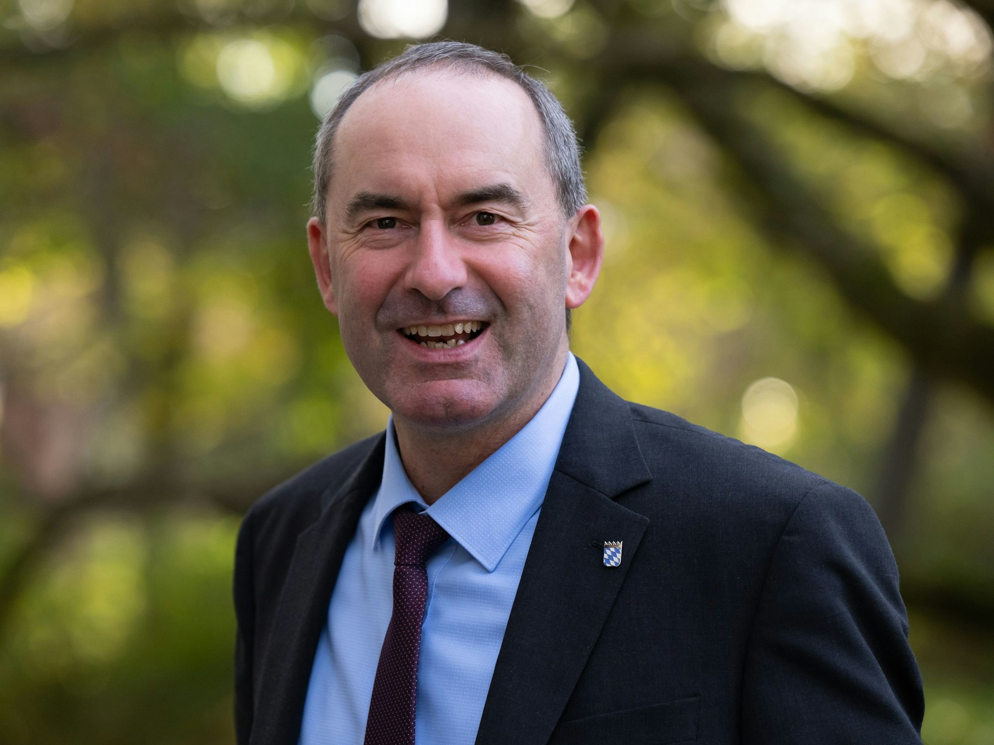 Hubert Aiwanger lächelt bei einer Pressekonferenz in die Kamera.