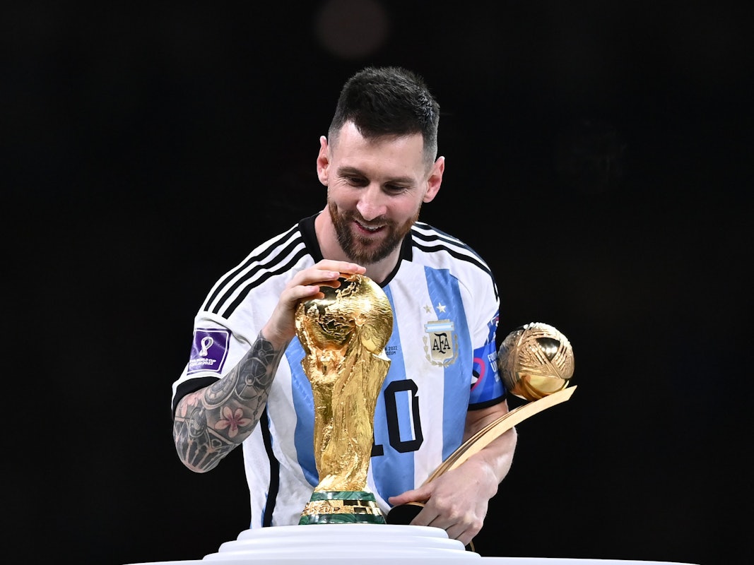 Lionel Messi berührt den Weltmeisterpokal.