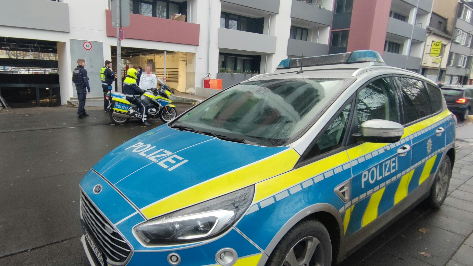 Einsatzkräfte der Polizei stehen vor einem Wohnhaus in Köln-Mülheim. Dort wurde ein Mann festgenommen.