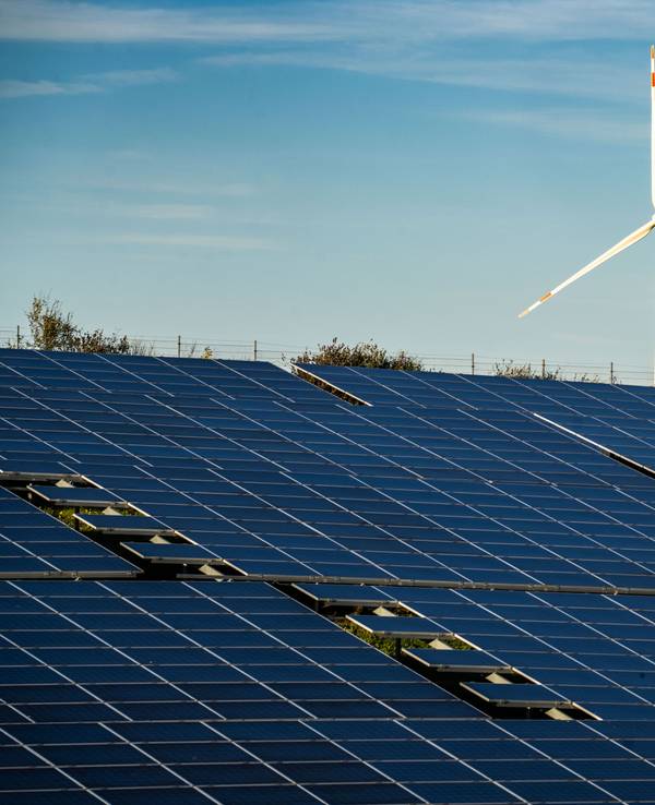 Ein Windrad steht auf einem Hügel oberhalb einer großflächigen Solaranlage auf einem Feld im Landkreis Alzey-Worms.