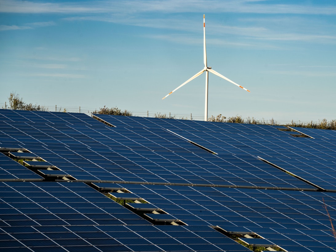 Ein Windrad steht auf einem Hügel oberhalb einer großflächigen Solaranlage auf einem Feld im Landkreis Alzey-Worms.