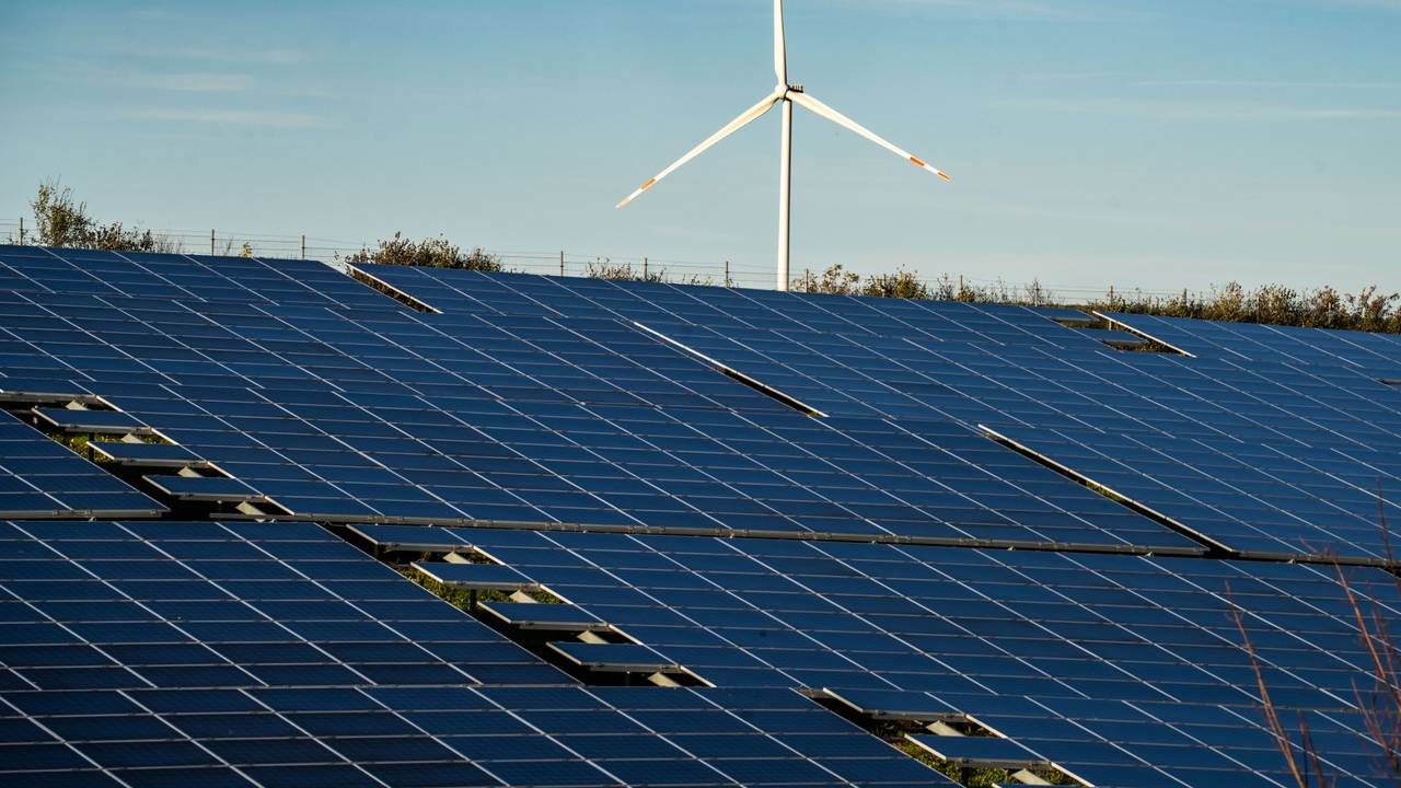 Ein Windrad steht auf einem Hügel oberhalb einer großflächigen Solaranlage auf einem Feld im Landkreis Alzey-Worms.