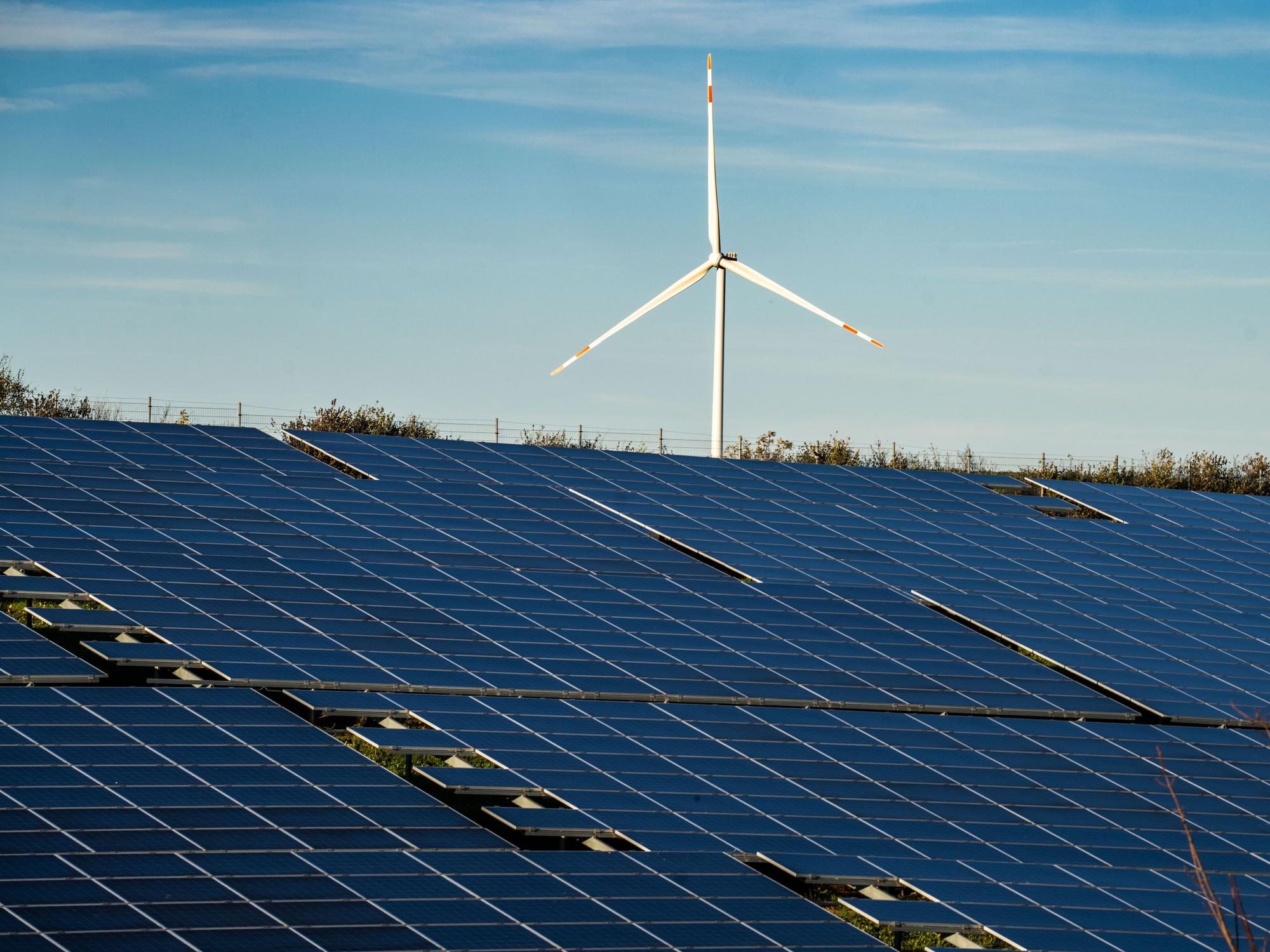 Ein Windrad steht auf einem Hügel oberhalb einer großflächigen Solaranlage auf einem Feld im Landkreis Alzey-Worms.