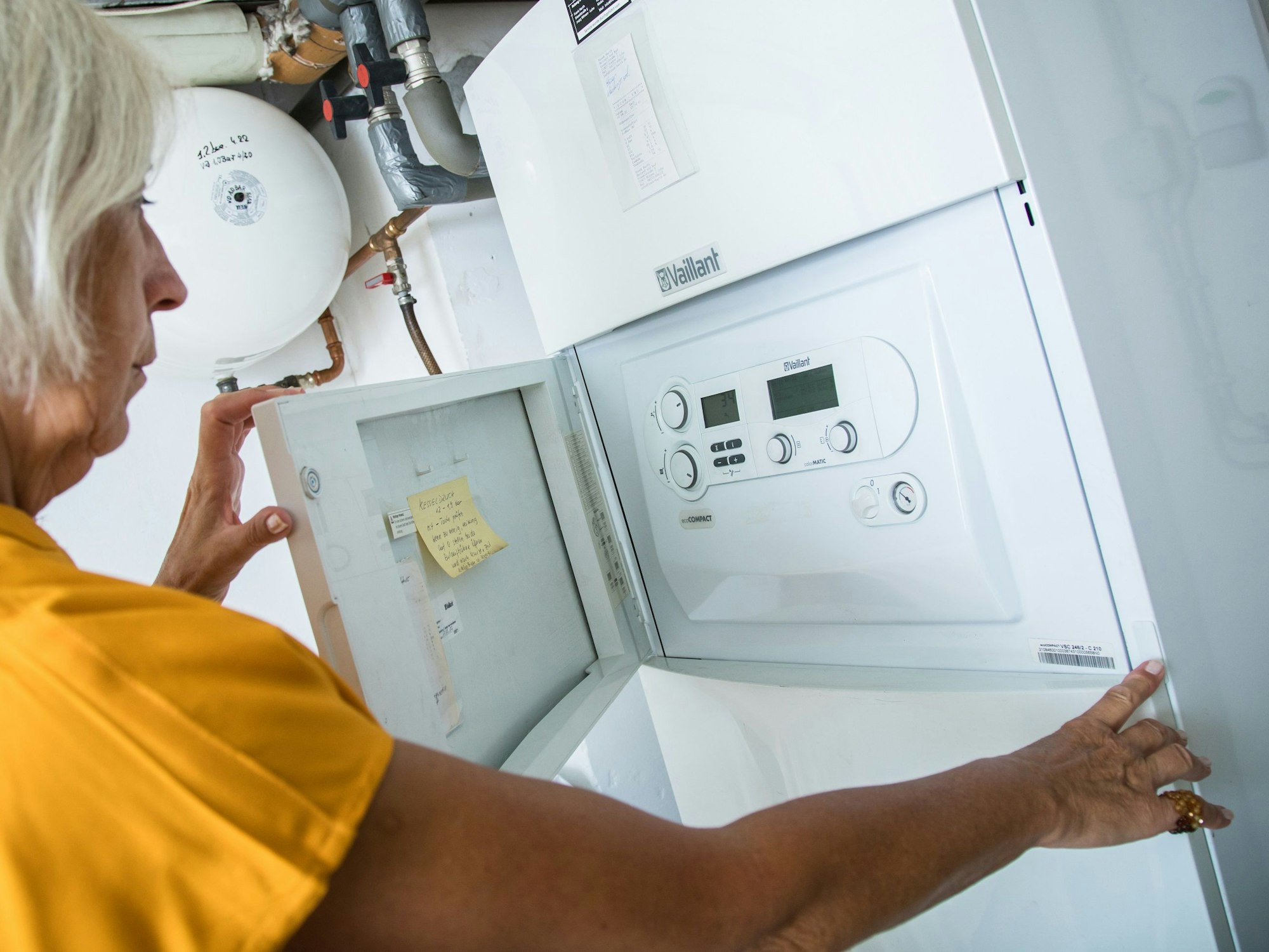 Eine Frau senkt in unserem Symbolbild die Vorlauftemperatur an ihrer Heizung.