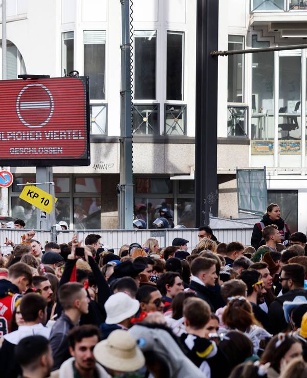 Zahlreiche Karnevalisten stehen an einer Absperrung, da Polizeibeamte den Zugang zur Zülpicher Straße wegen Überfüllung abgeriegelt haben.