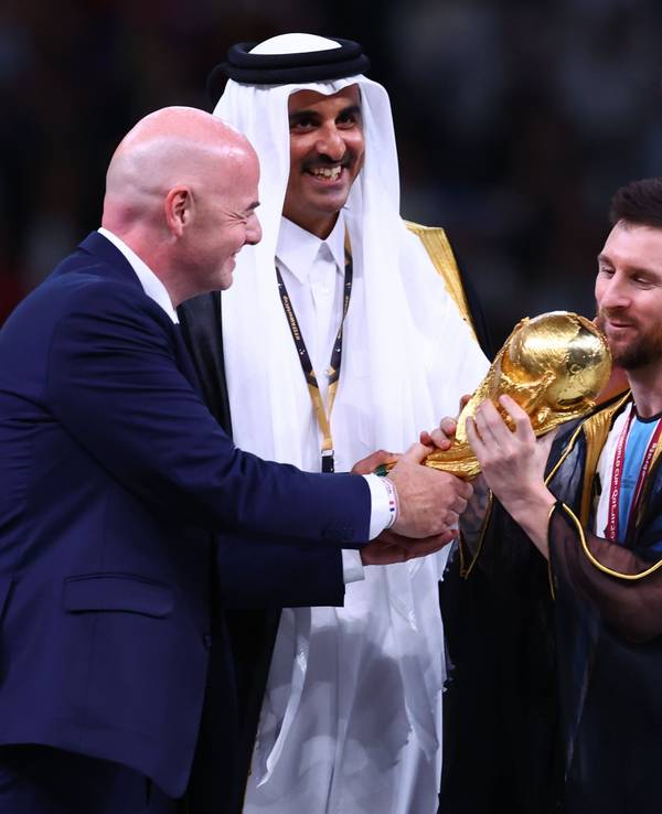 Argentiniens Lionel Messi (r) nimmt den Weltmeisterpokal vom Emir von Katar, Scheich Tamim bin Hamad Al Thani (M) und FIFA-Präsident Gianni Infantino entgegen.