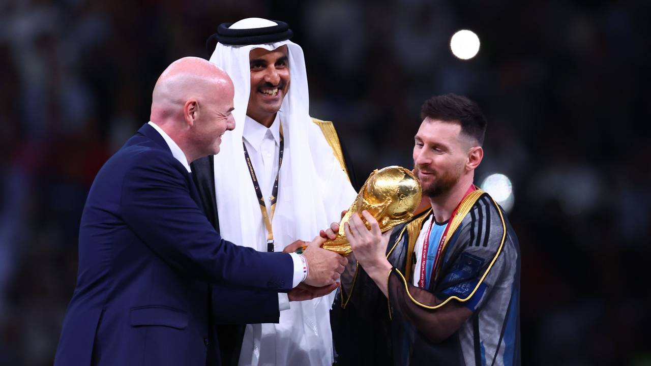 Argentiniens Lionel Messi (r) nimmt den Weltmeisterpokal vom Emir von Katar, Scheich Tamim bin Hamad Al Thani (M) und FIFA-Präsident Gianni Infantino entgegen.