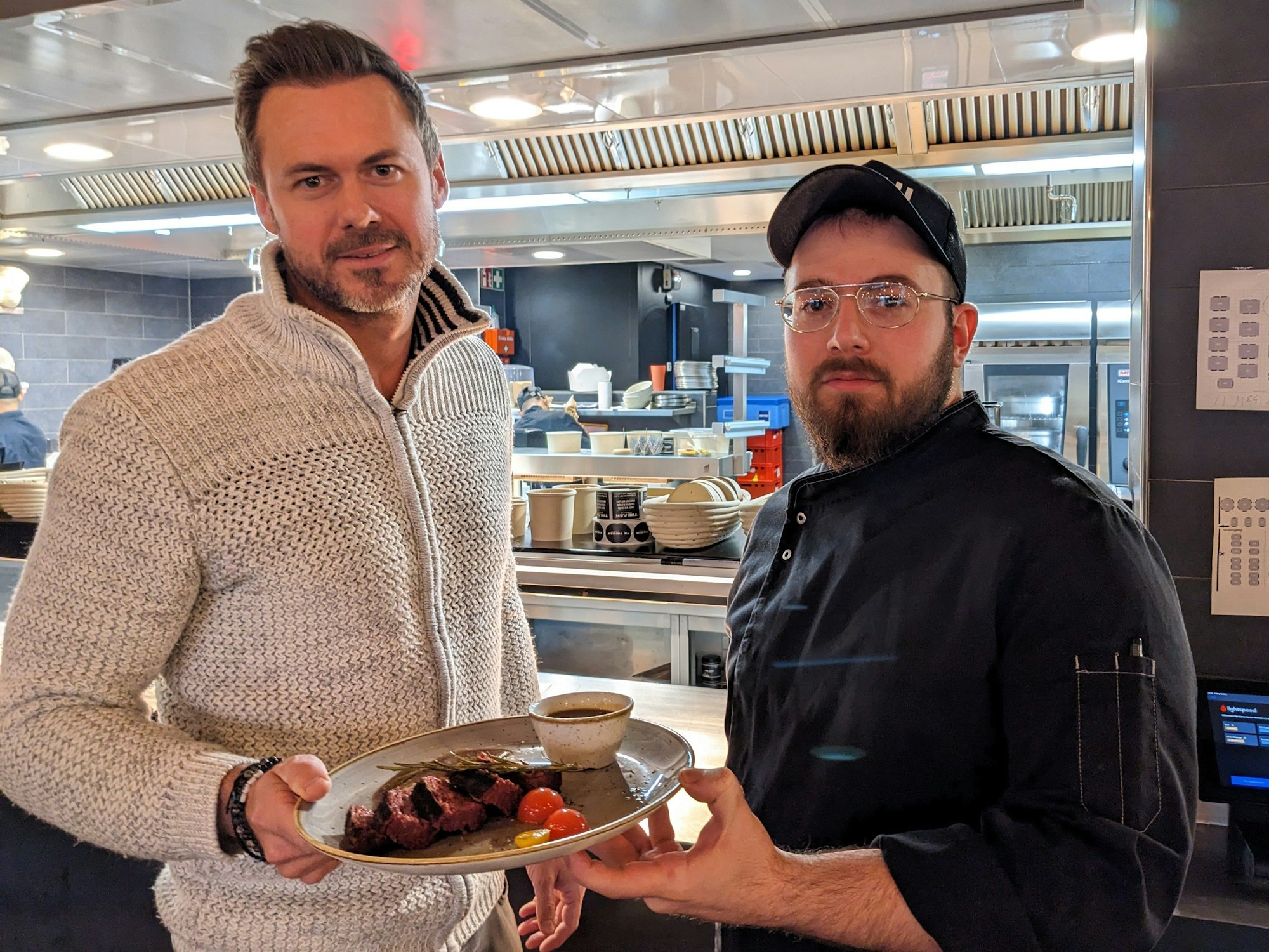 Benjamin Walter hält gemeinsam mit Küchenchef Cem einen Teller, auf dem ein 3D-Steak liegt.