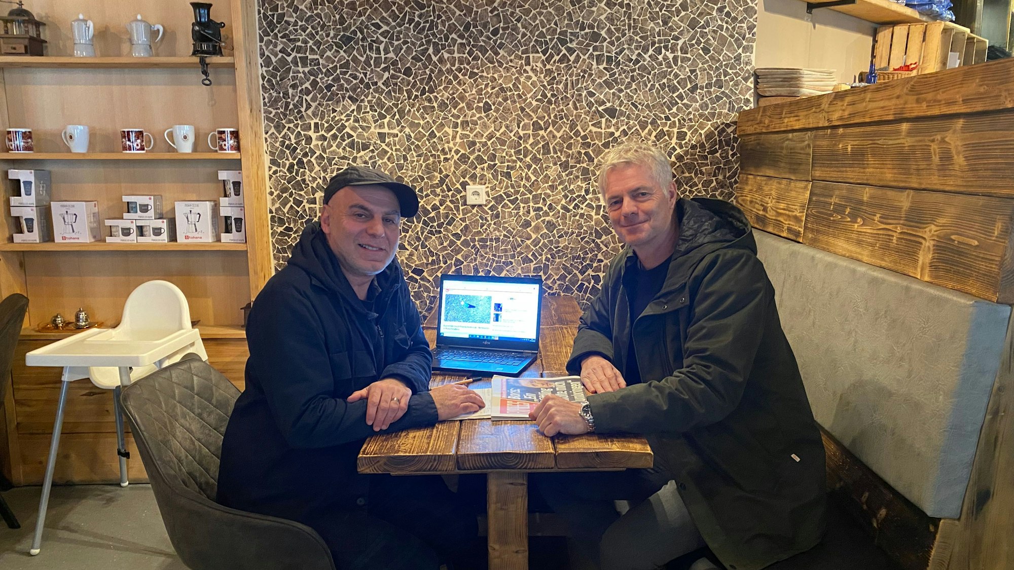 EXPRESS-Reporter Ayhan Demirci sitzt mit ARD-Kommentator Tom Bartels am Tisch.