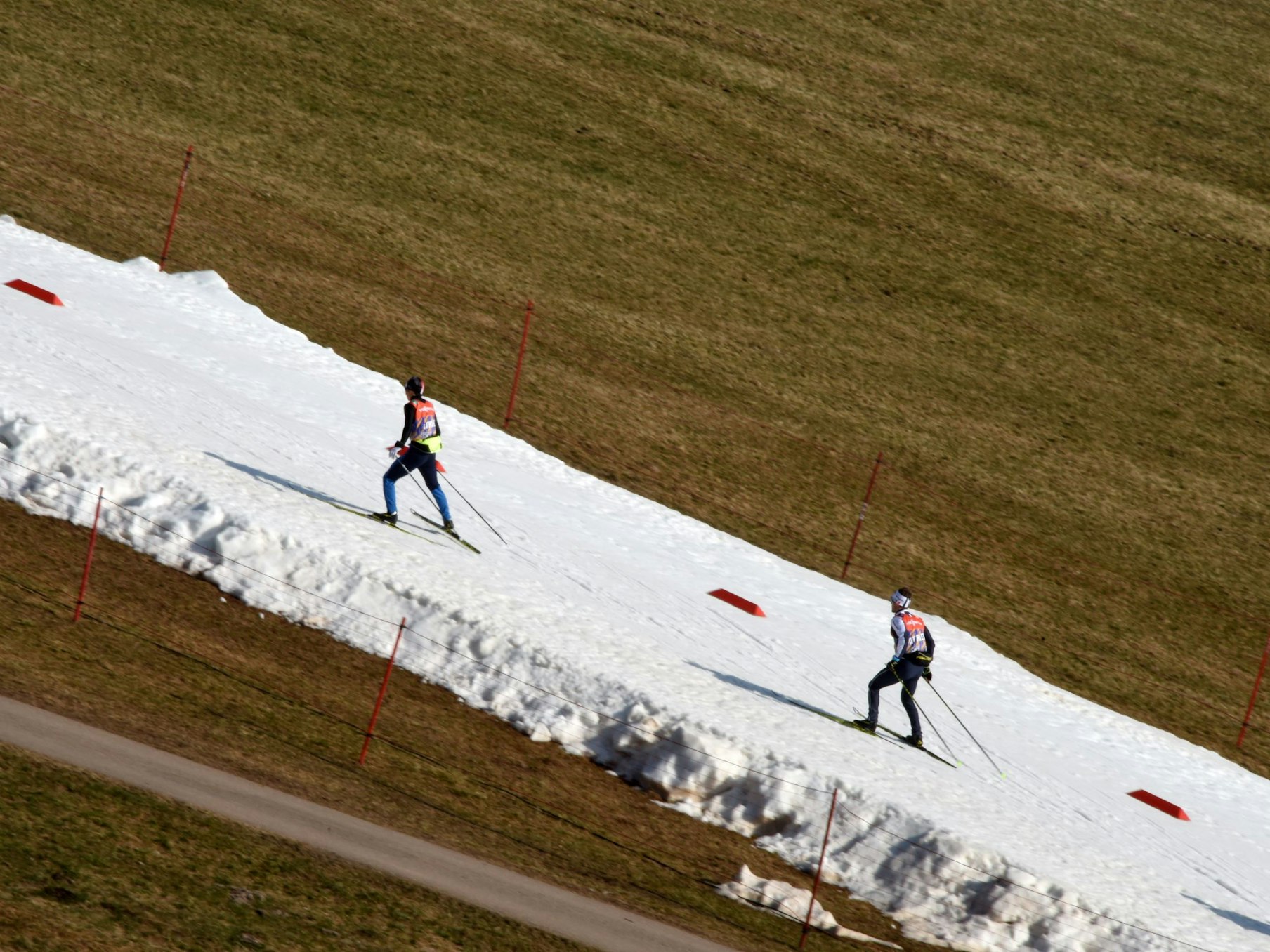 Athleten trainieren in der Langlaufspur. Durch die milden Temperaturen steht den Athleten nur ein schmales Schneeband zur Verfügung.