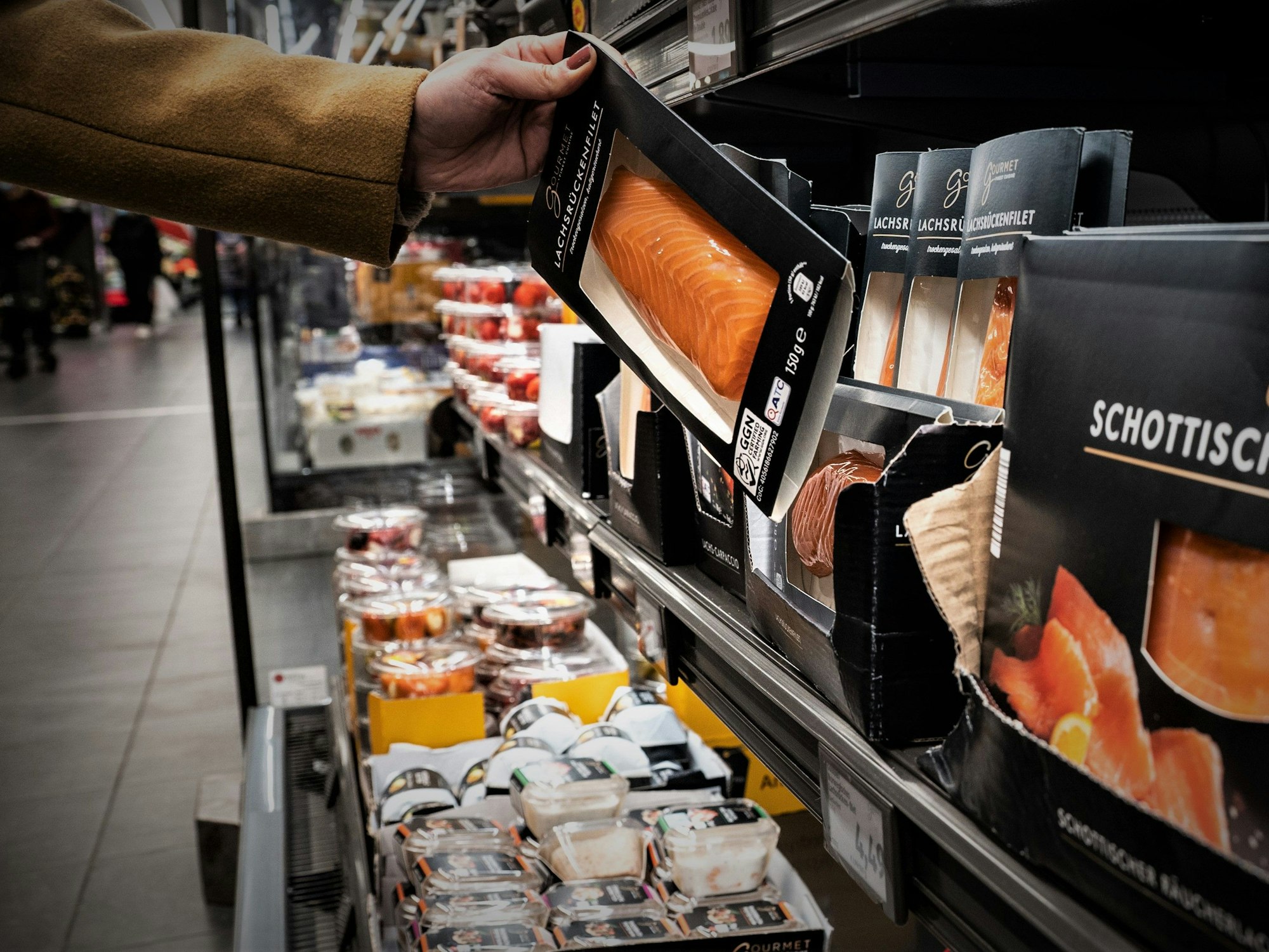 Eine Frau nimmt in einer Aldi-Filiale eine Packung Lachs aus der Kühlung (Archivbild): Der Aldi-Süd-Deutschlandchef hat bestätigt, dass bald eine alte Tradition in den Filialen enden wird.