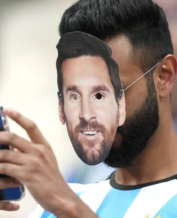 Ein Fan mit der Gesichtsmaske von Argentiniens Lionel Messi bedient sein Smartphone.