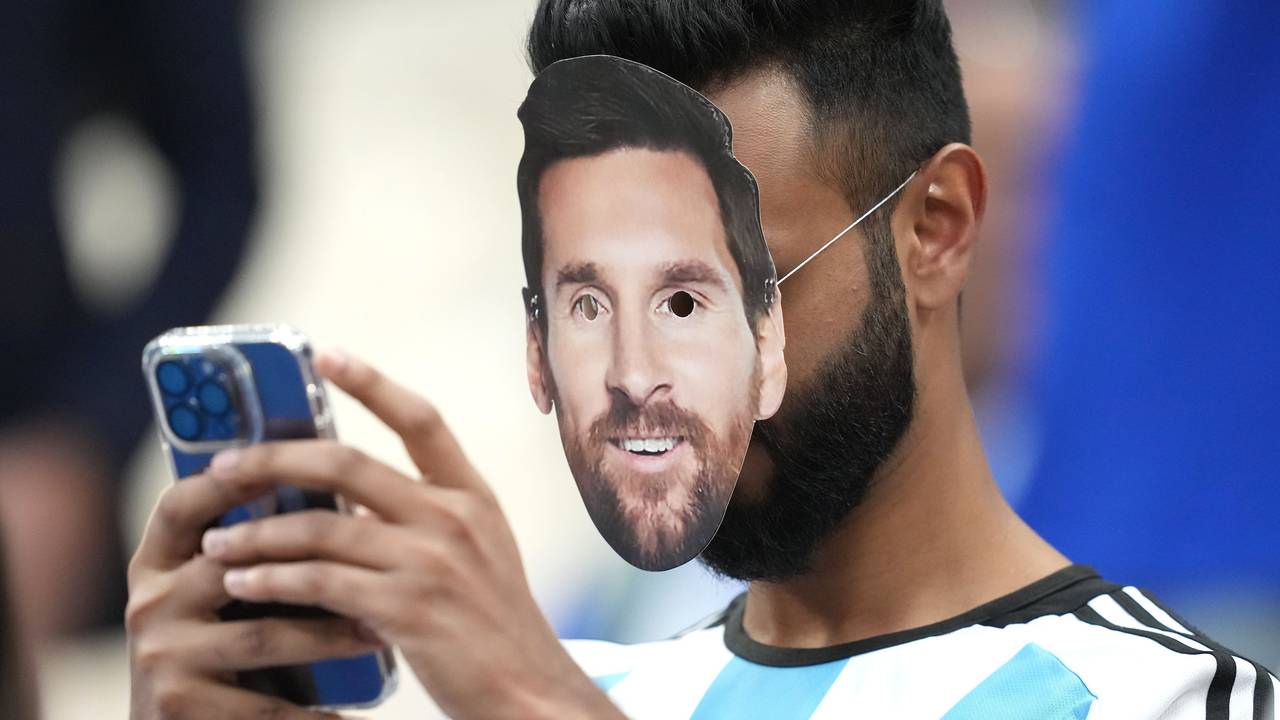 Ein Fan mit der Gesichtsmaske von Argentiniens Lionel Messi bedient sein Smartphone.