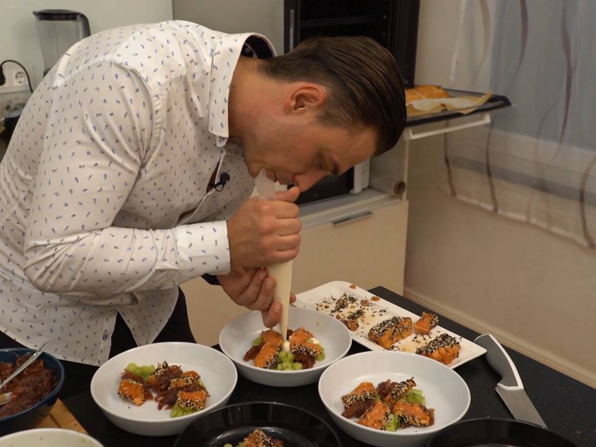 „Das perfekte Dinner“-Kandidat Tomek verziert seine Lachs-Vorspeise in der Küche.