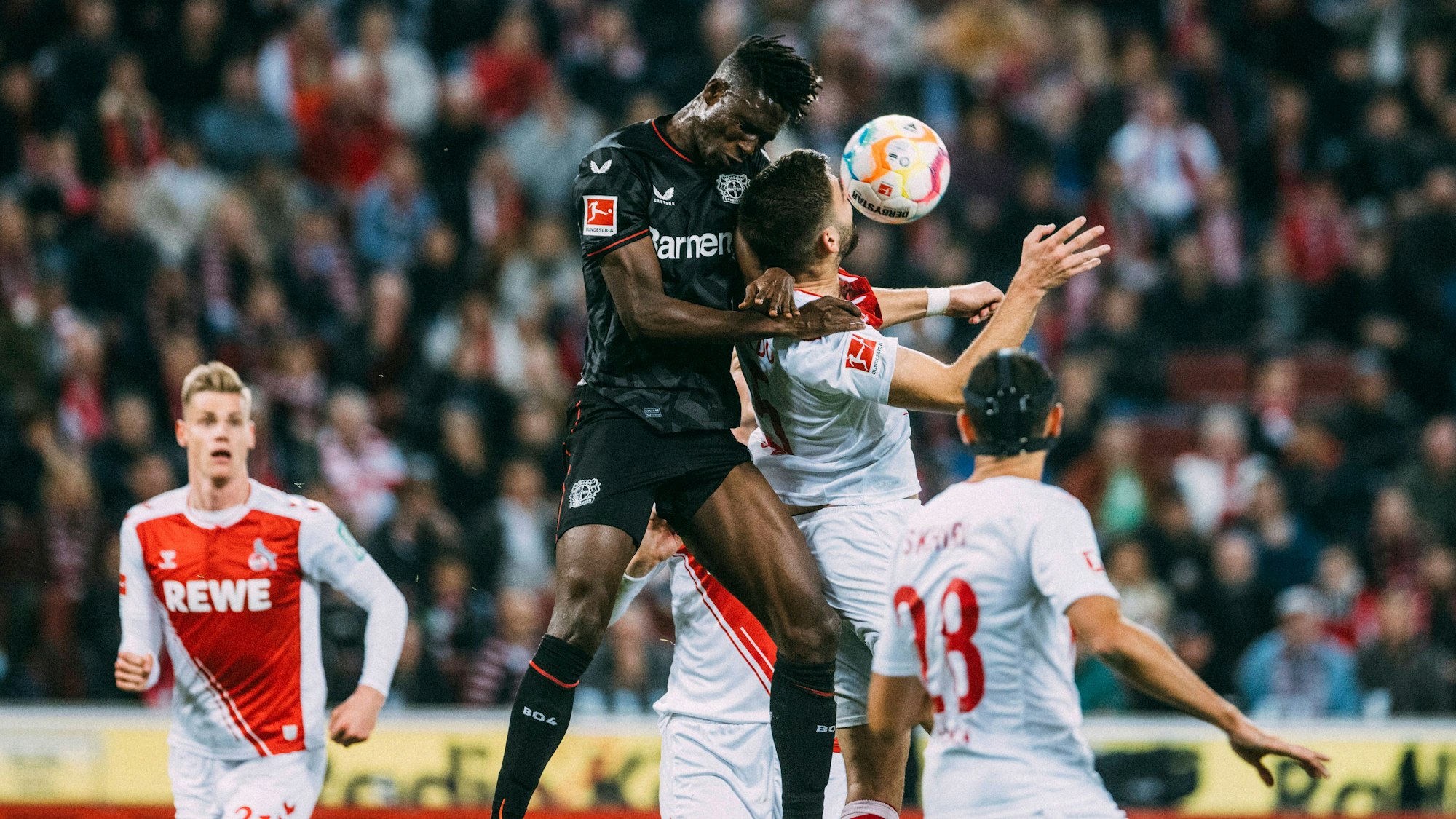 Odilon Kossounou von Bayer Leverkusen beim Kopfballduell mit Nikola Soldo vom 1. FC Köln.