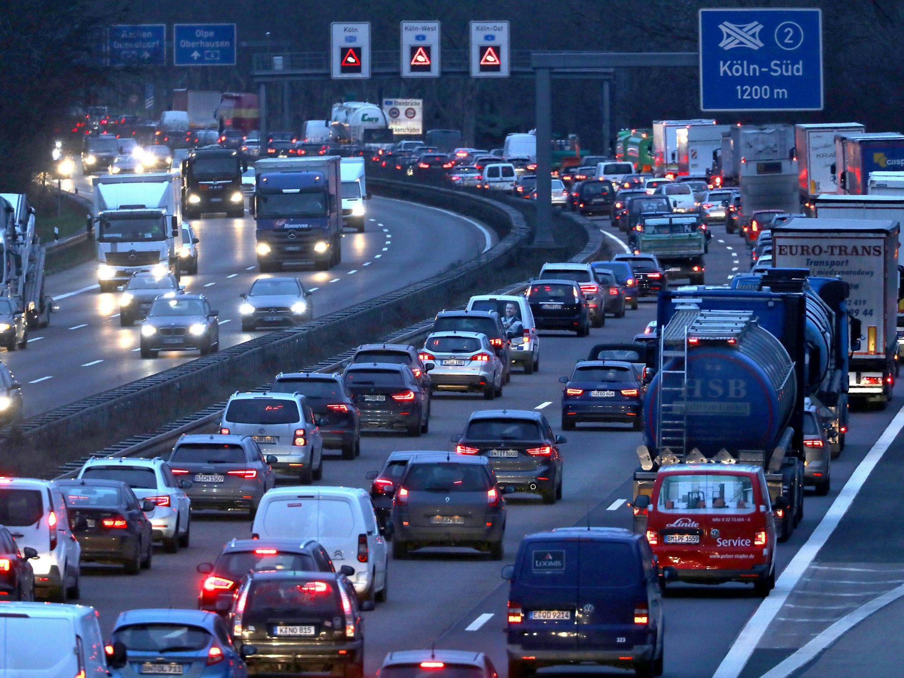 Stau auf der A555 in Köln. Die Autos haben in der Dämmerung ihre Lichter eingeschaltet.