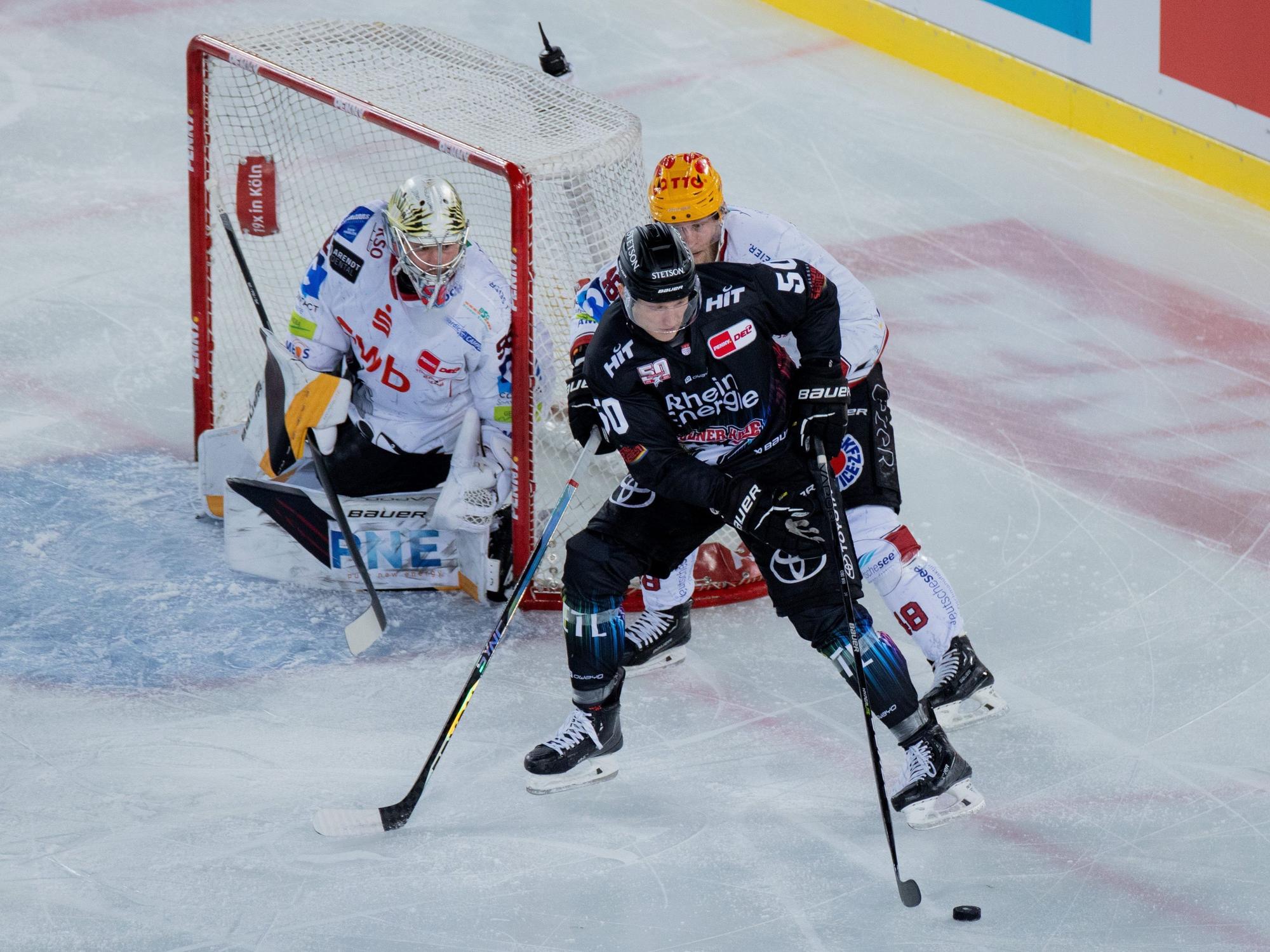 Kölns Alexander Oberlinger (vorne) und Braunschweigs Nicholas Jensen versuchen an den Puck zu kommen.