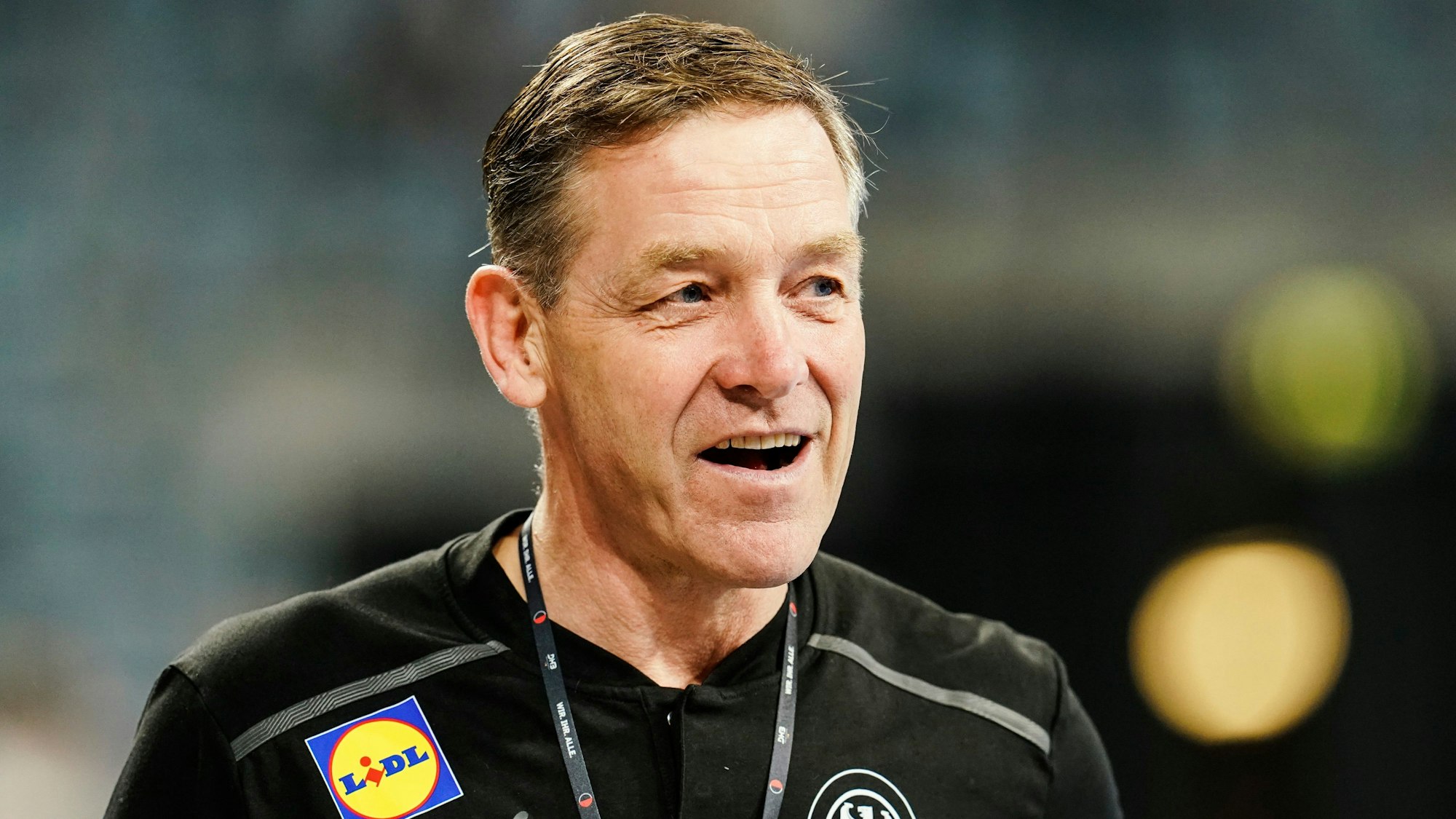 Handball-Bundestrainer zeigt sich mit guter Laune beim Spiel seiner deutschen Mannschaft gegen Schweden.