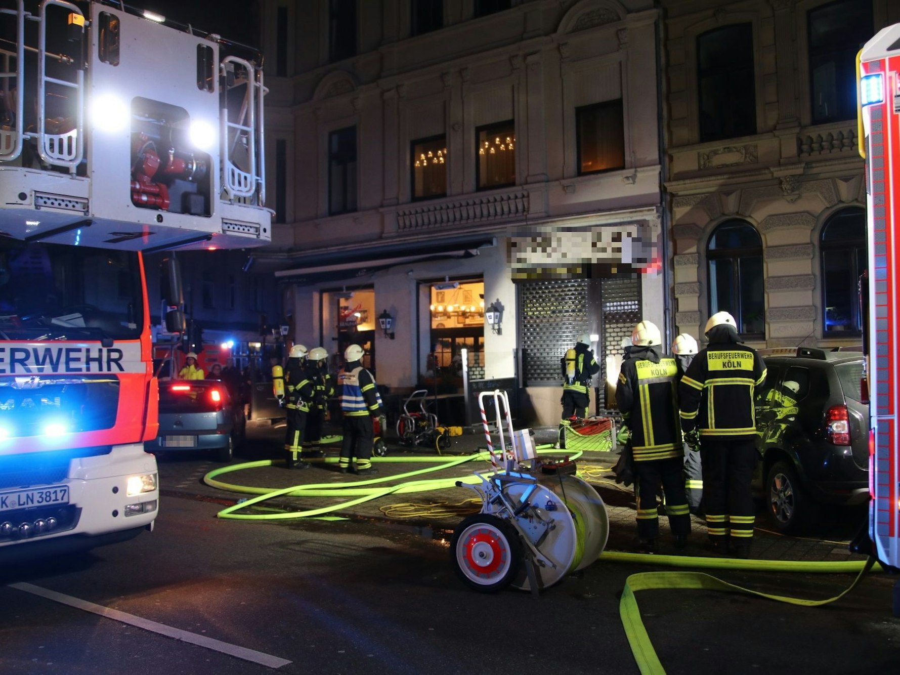 Einsatzkräfte der Feuerwehr stehen vor einem Schmuckgeschäft in Köln. Sie müssen zunächst die Sicherheitsvorkehrungen durchbrechen.