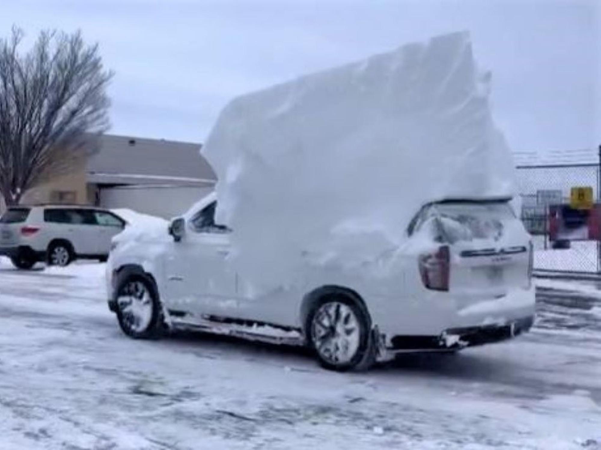 Ein mit Schnee bedecktes Auto fährt in der US-Stadt Buffalo über eine Straße.