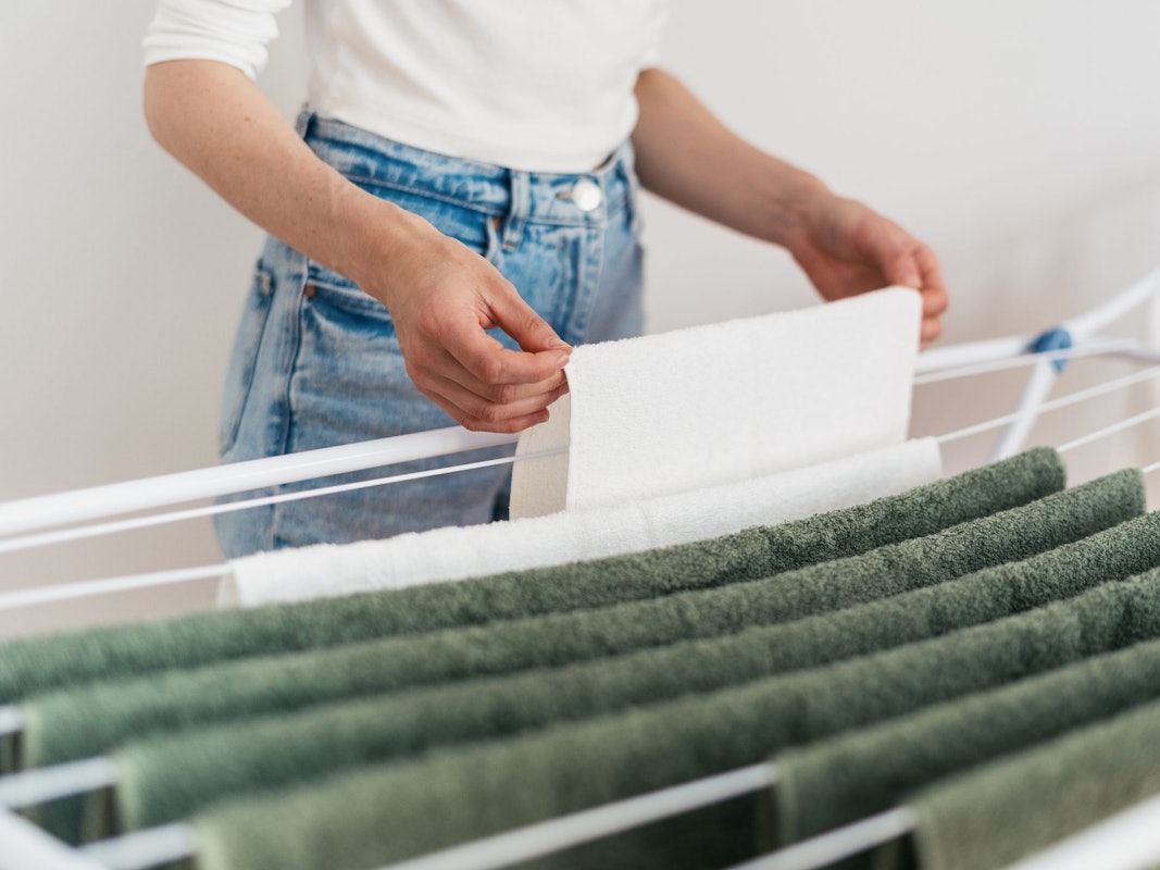 Eine Frau hängt Wäsche auf einen Wäscheständer.