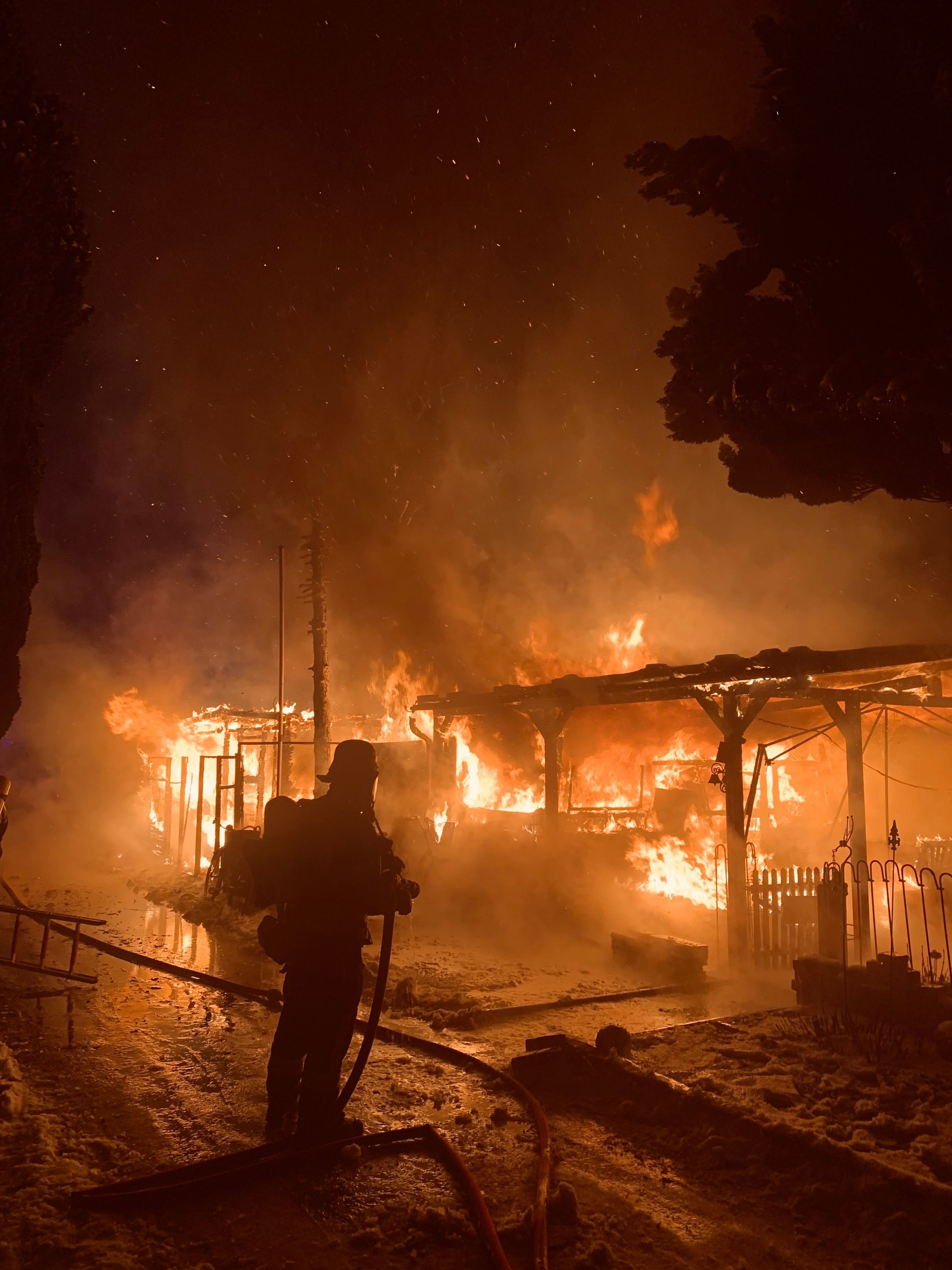 Ein Mitglied der Augsburger Feuerwehr bekämpft ein Feuer auf einem Campingplatz.
