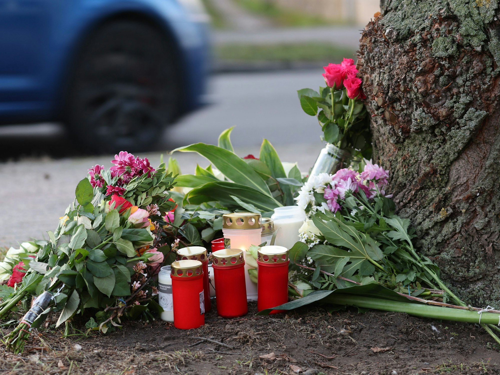 Blumen, Kerzen und Grablichter stehen am Straßenrand an einem Baum, wo am Morgen des 26.12.2022 eine 23-jährige Frau tot gefunden wurde.