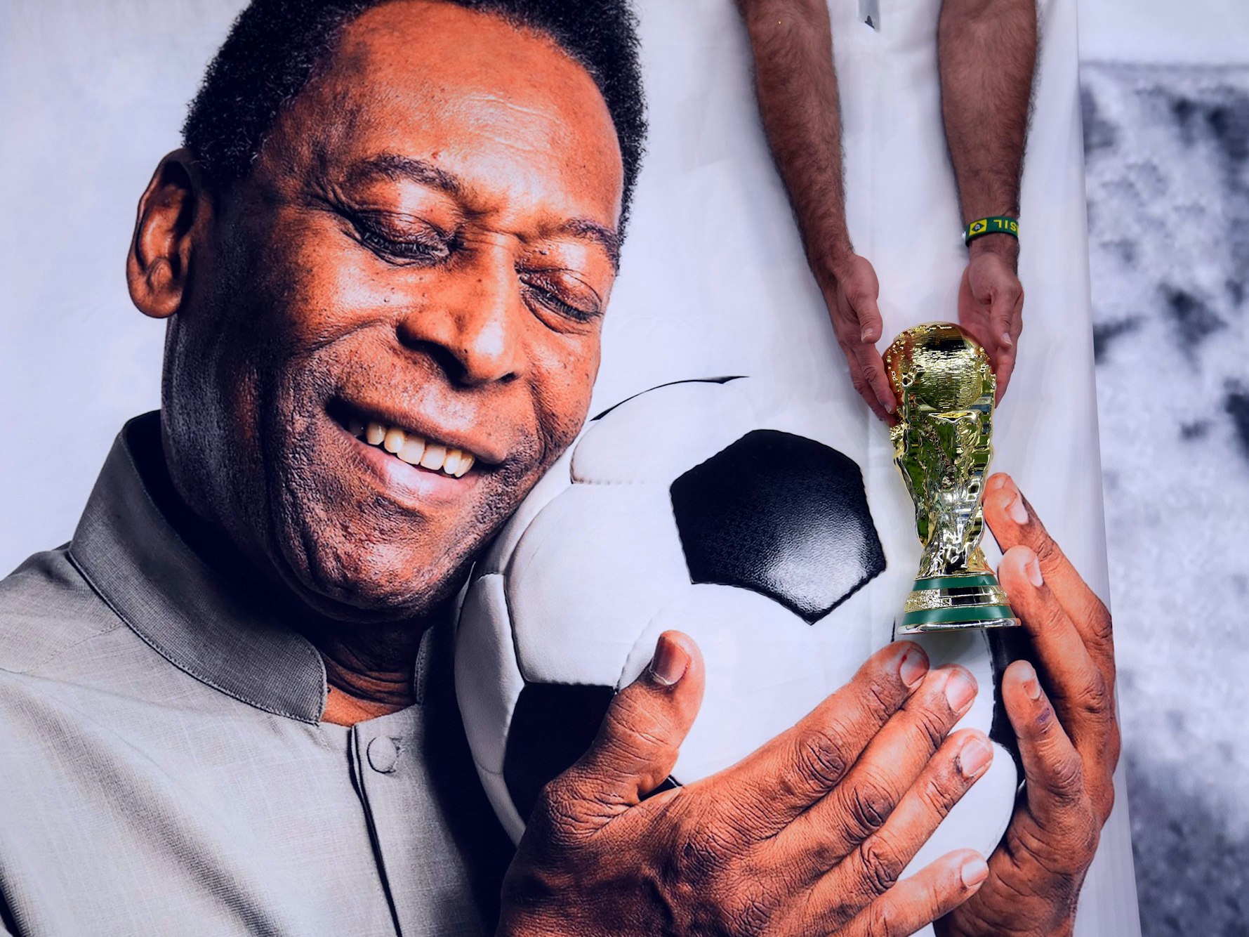 Lusail Stadion in Katar: ein brasilianischer Fan hält vor dem Spiel eine nachgebildete WM-Trophäe neben das Bild des ehemaligen brasilianischen Nationalspielers Pelé.