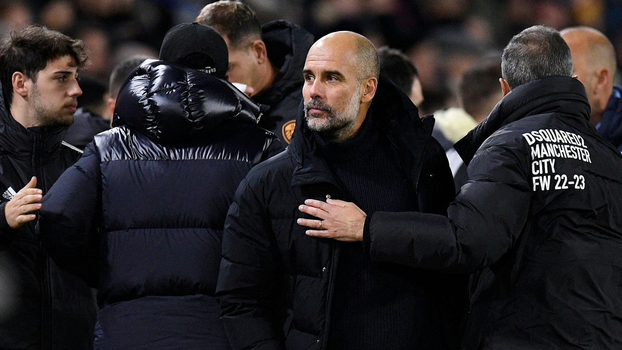 Pep Guardiola inmitten von Menschen.