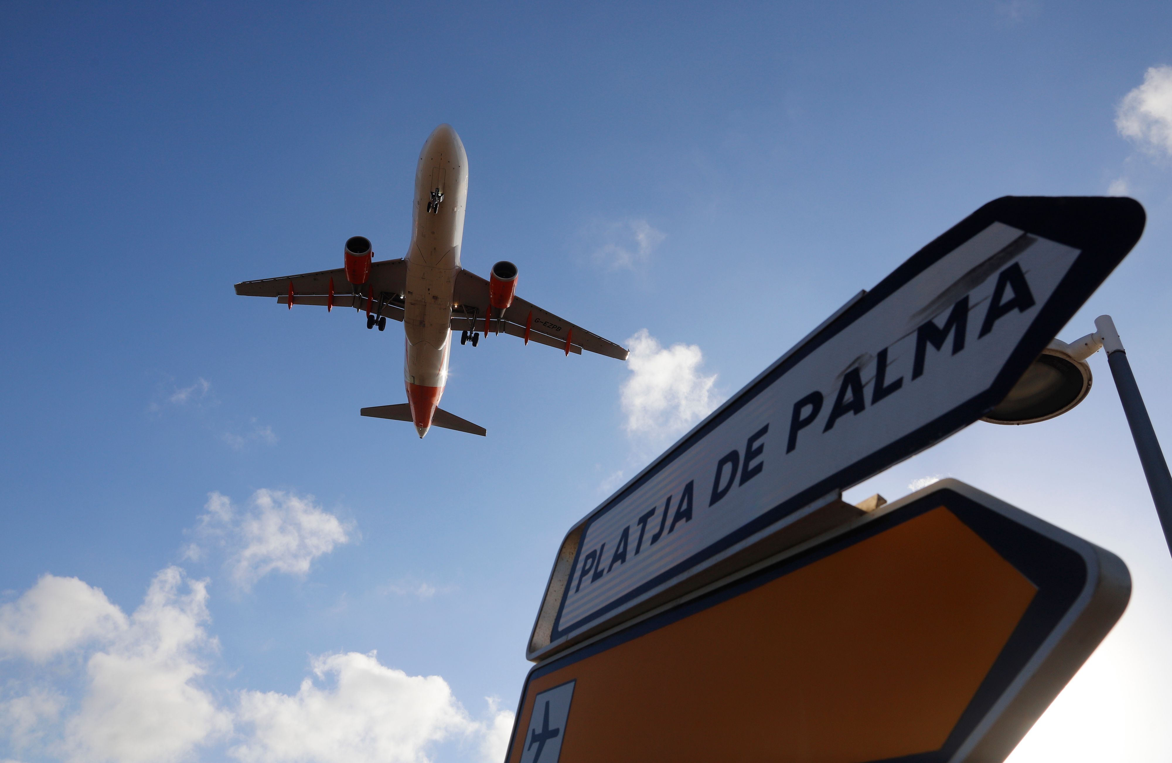 Ein Flugzeug überfliegt bei der Landung auf Mallorca ein Schild, das die Richtung nach Playa de Palma anzeigt.