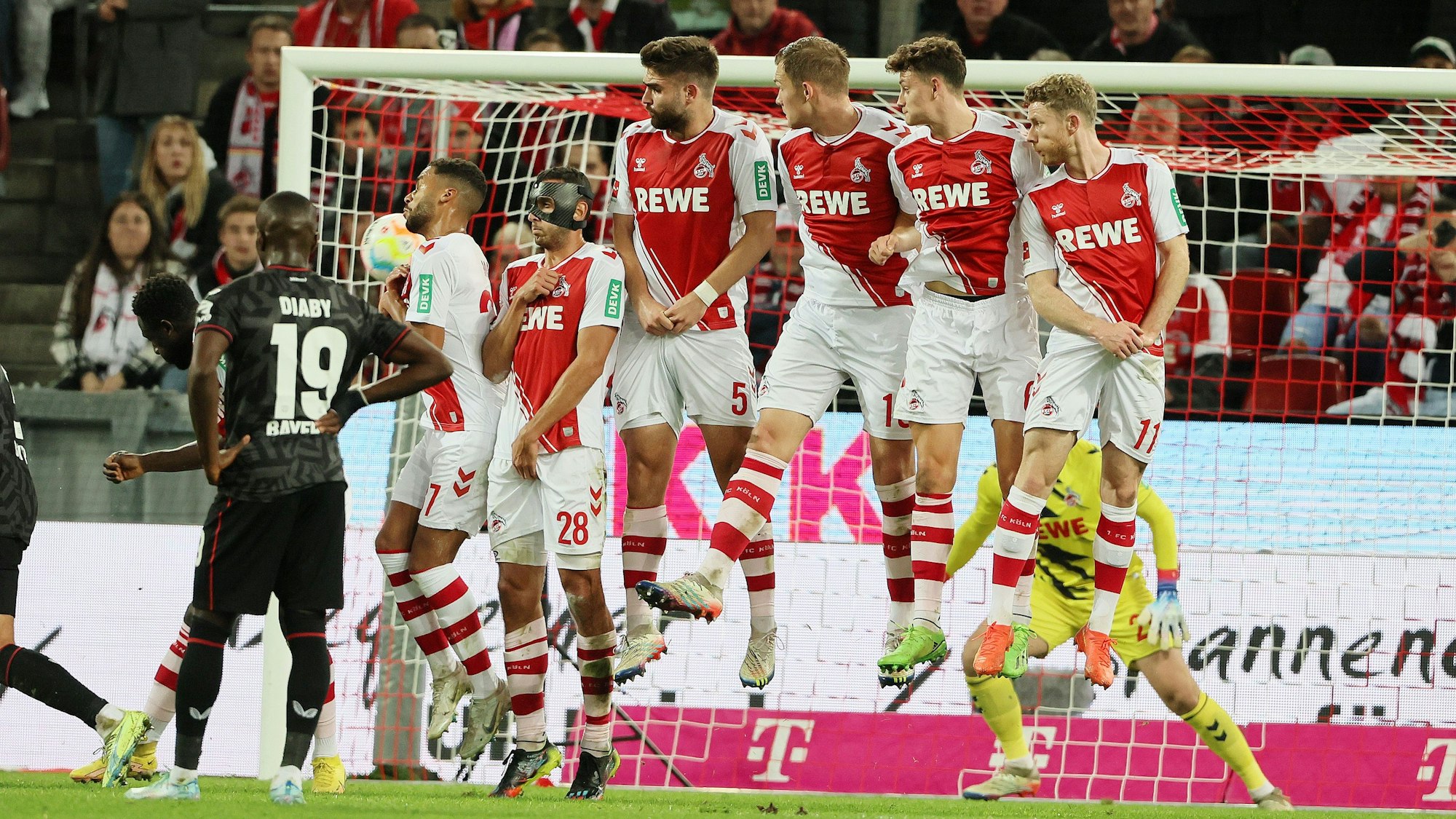 Die Spieler des 1. FC Köln springen in der Mauer hoch.