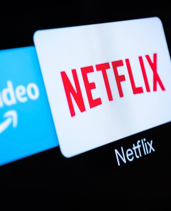 Auf einem Fernseher in einer Wohnung sind verschiedene Streaming-Dienste (Amazon Prime Video, Netflix, Spotify) geöffnet.