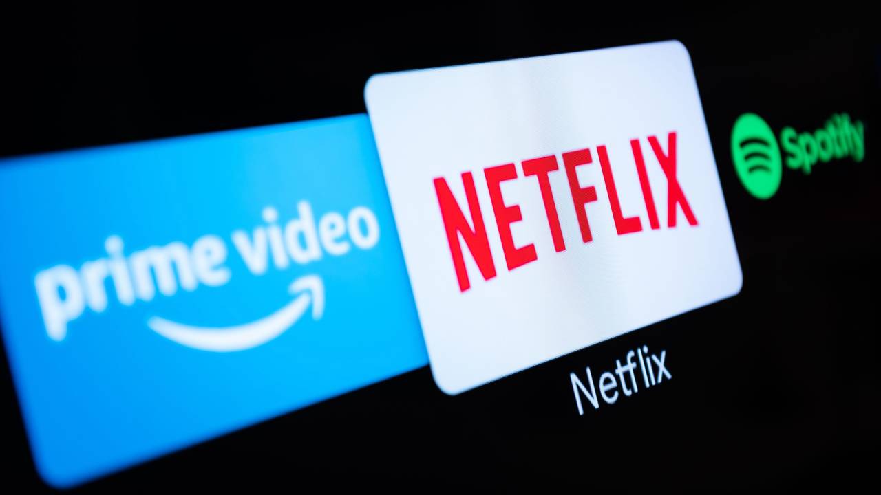 Auf einem Fernseher in einer Wohnung sind verschiedene Streaming-Dienste (Amazon Prime Video, Netflix, Spotify) geöffnet.